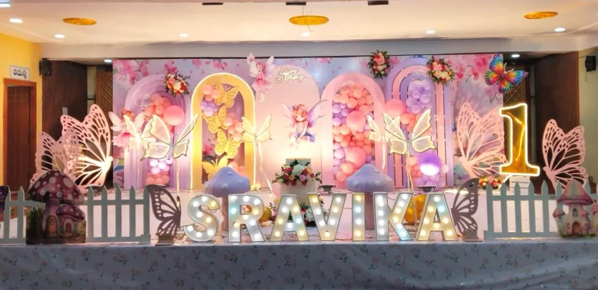butterfly theme decor for 1st birthday party with wooden frames, cake table and LED name and butterflies.