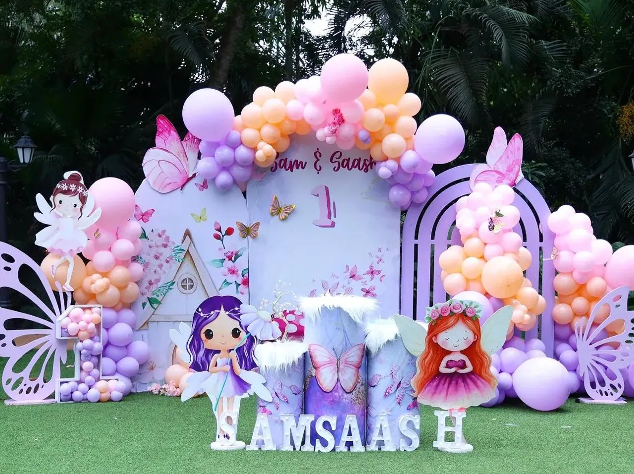 Outdoor first birthday stage with a floral arch